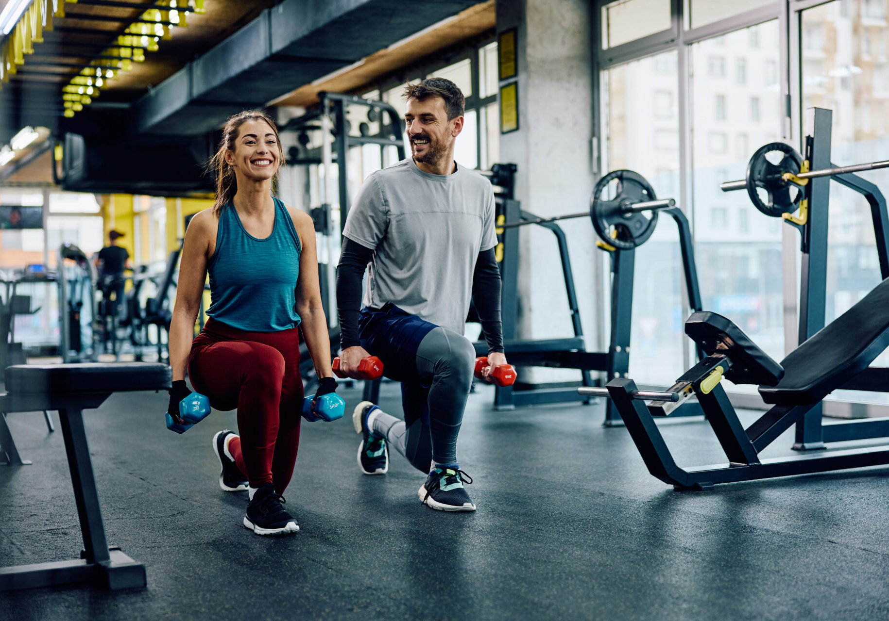 Couple working out with dumbbells in gym.